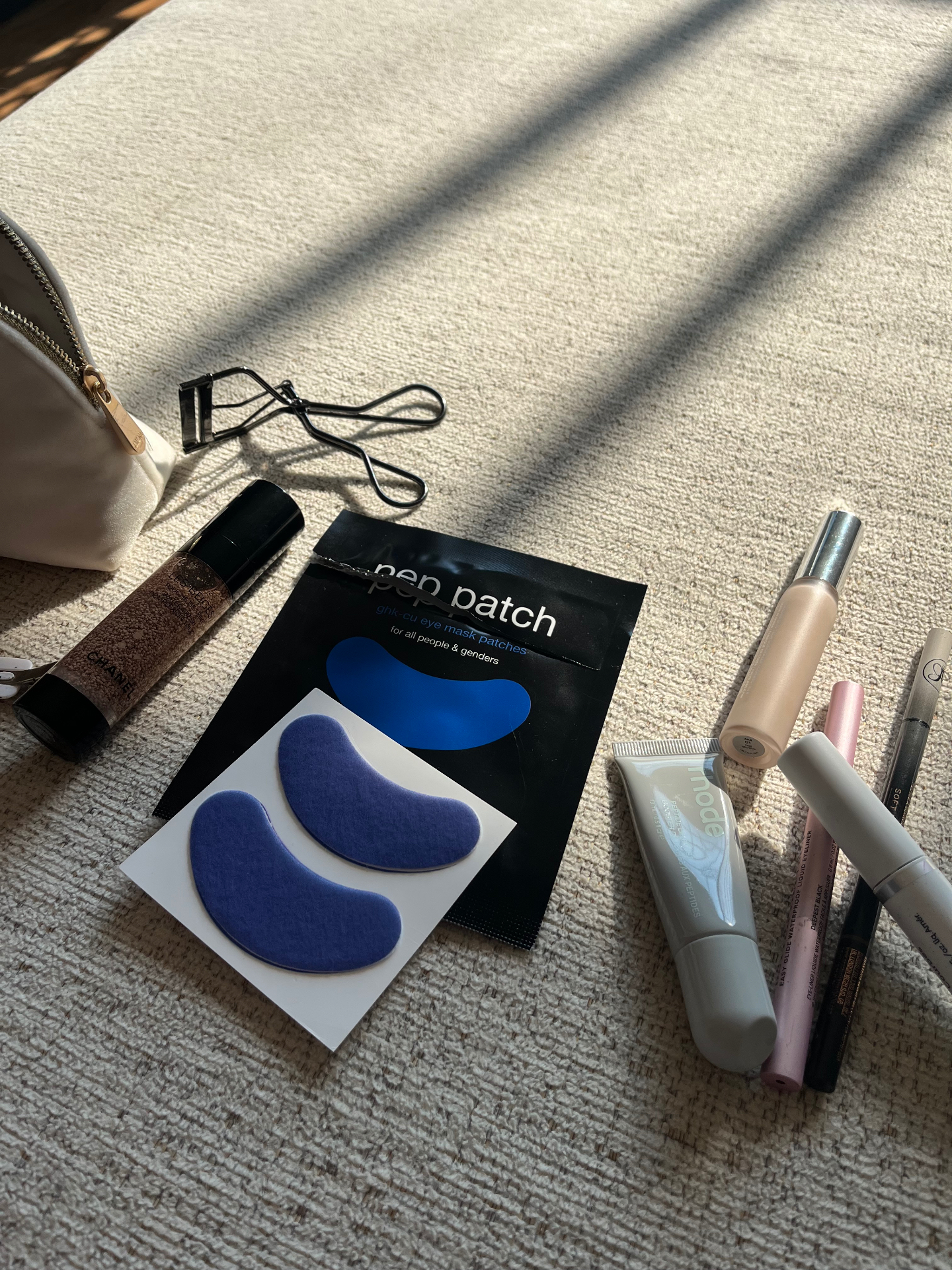 Pep Patch eye patches and sachet beside makeup essentials in warm morning sunlight